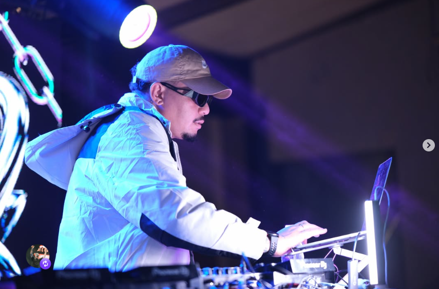 DJ Wallow de jaqueta branca mixando sob luz azul e roxa
